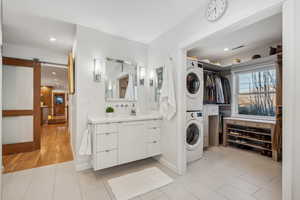 Bathroom featuring stacked washer / drying machine, tile patterned flooring, and vanity