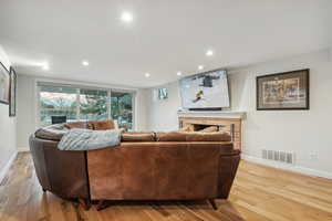 Living room with plenty of natural light, light wood-type flooring, and a brick fireplace