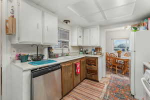 Kitchen featuring sink, white appliances, white cabinetry, and plenty of natural light