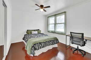 Bedroom with ceiling fan, wood-type flooring, and ornamental molding