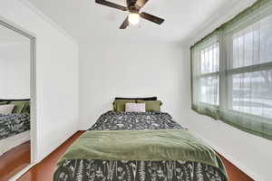 Bedroom featuring ceiling fan, hardwood / wood-style flooring, and crown molding