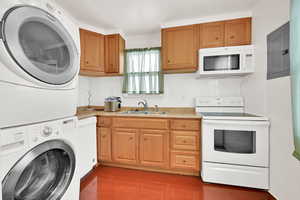 Kitchen with white appliances, stacked washer / dryer, electric panel, sink, and dark hardwood / wood-style floors