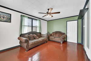 Living room featuring ceiling fan, dark hardwood / wood-style flooring, and ornamental molding