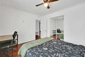 Bedroom featuring ceiling fan, dark hardwood / wood-style flooring, and ornamental molding