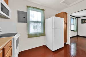 Kitchen featuring ornamental molding, white appliances, electric panel, and dark hardwood / wood-style flooring