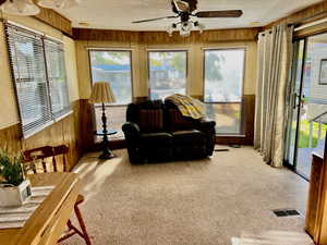 Sunroom featuring wooden walls, carpet flooring, and wainscoting