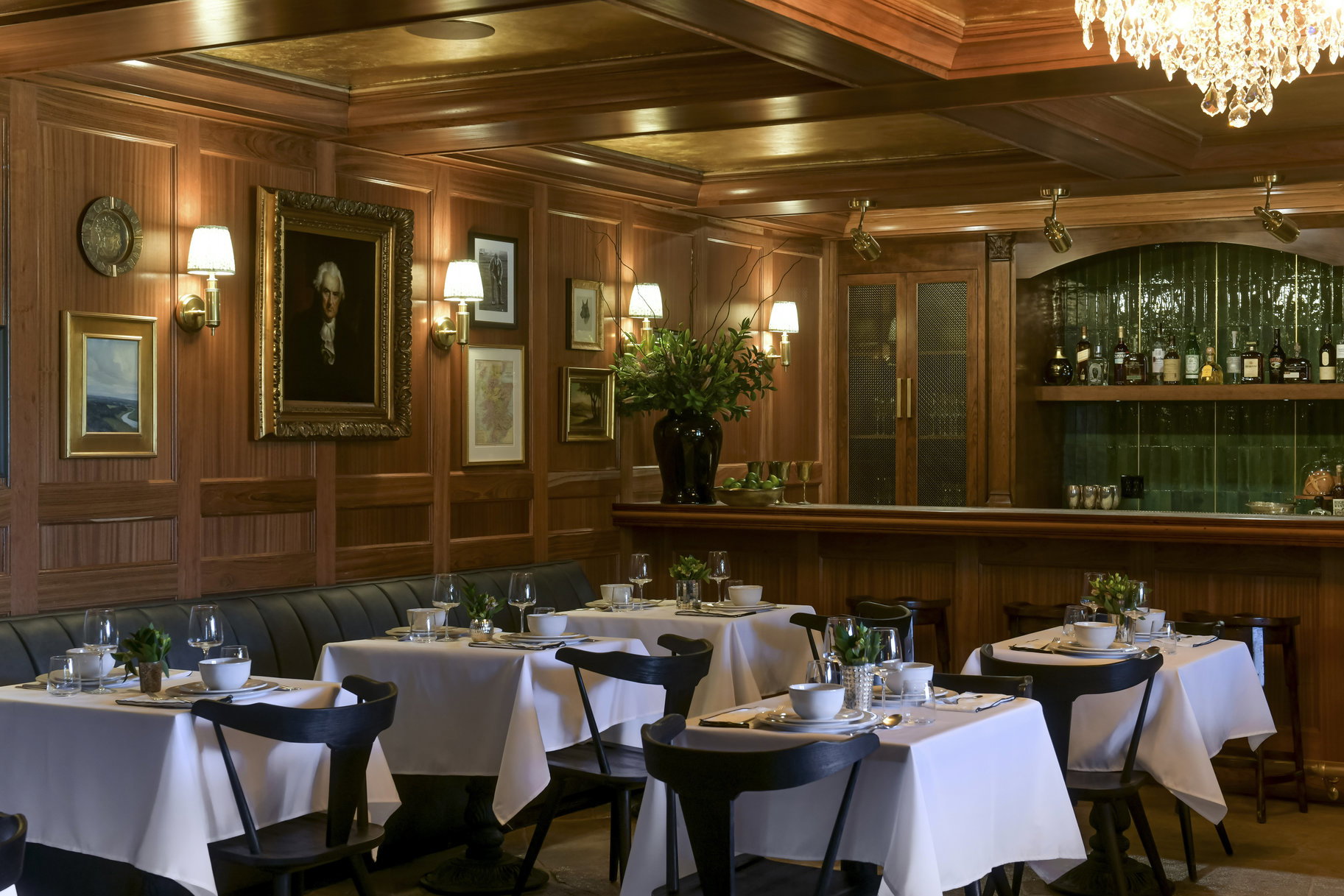 Bar featuring beamed ceiling, an inviting chandelier, coffered ceiling, and wooden walls