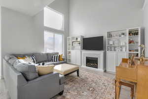 Living room with light hardwood / wood-style flooring and a towering ceiling