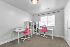 Home office featuring a textured ceiling and light carpet