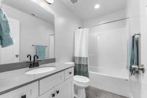 Full bathroom with shower / bathtub combination with curtain, vanity, and toilet