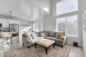 Living room with a towering ceiling, a chandelier, and light hardwood / wood-style floors