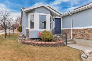 Doorway to property with stone siding, stucco siding, and a yard