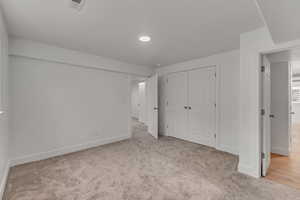 Unfurnished bedroom with light carpet and a closet