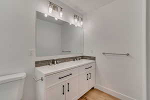 Bathroom with hardwood / wood-style flooring, tasteful backsplash, vanity, and toilet