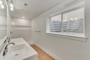 Bathroom with hardwood / wood-style flooring, vanity, and a shower