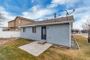 Rear view of house featuring a shingled roof, a lawn, fence, a patio area, and stucco siding