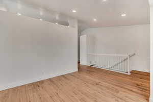 Empty room with light hardwood / wood-style floors and vaulted ceiling