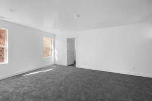 Spare room featuring dark carpet and a textured ceiling