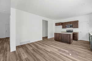 Kitchen featuring appliances with stainless steel finishes, a kitchen island, light hardwood / wood-style floors, and dark brown cabinets