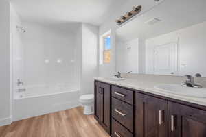 Full bathroom with hardwood / wood-style flooring, tub / shower combination, toilet, a textured ceiling, and vanity