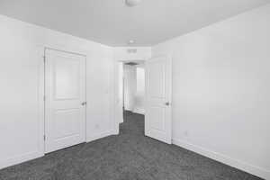 Unfurnished bedroom featuring a textured ceiling and dark colored carpet