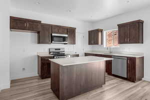 Kitchen with a center island, appliances with stainless steel finishes, sink, and light wood-type flooring