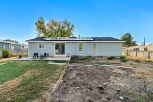 Back of house featuring a patio, cooling unit, a lawn, and solar panels