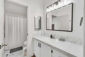 Bathroom with toilet, a shower with curtain, and vanity