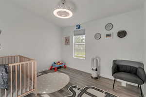 Bedroom with a crib and hardwood / wood-style floors