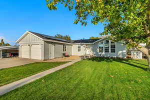 Ranch-style home with solar panels, a front lawn, and a garage