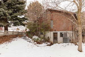 Snow covered back of property with central AC