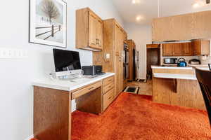 Kitchen featuring kitchen peninsula, stainless steel refrigerator, a breakfast bar area, and multiple ovens