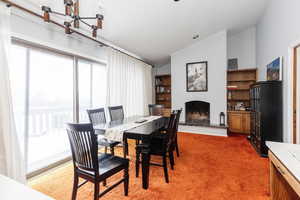 Carpeted dining space with a chandelier and lofted ceiling