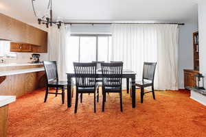 Carpeted dining space with an inviting chandelier