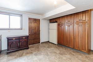 Interior space featuring a textured ceiling and white fridge