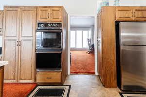 Kitchen featuring double oven, stainless steel fridge, and light brown cabinets