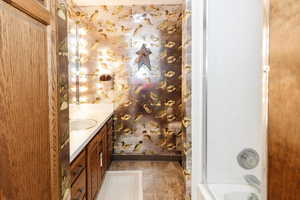 Bathroom with tiled shower / bath combo and vanity