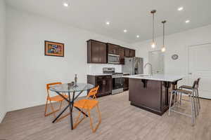 Kitchen featuring a breakfast bar area, backsplash, hanging light fixtures, a kitchen island with sink, and stainless steel appliances