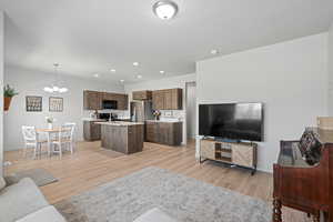 Living room featuring light hardwood / wood-style flooring, sink, an inviting chandelier, and a textured ceiling