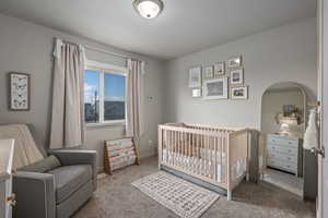 Carpeted bedroom with a textured ceiling and a nursery area