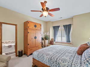 Carpeted bedroom featuring ensuite bathroom and ceiling fan