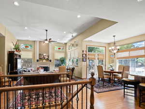 Living room featuring ceiling fan with notable chandelier and light wood-type flooring