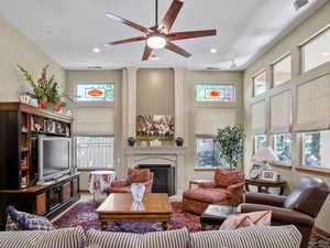 Living room featuring ceiling fan, plenty of natural light, and ornate columns