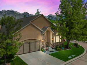 View of front of house with a garage, a mountain view, and a lawn