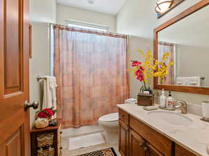 Full bathroom featuring shower / tub combo with curtain, vanity, toilet, and tile patterned flooring