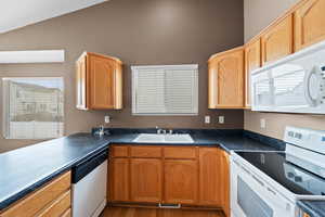 Kitchen featuring lofted ceiling, sink, white appliances, and light hardwood / wood-style floors