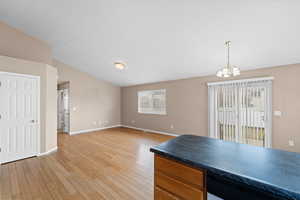 Kitchen featuring an inviting chandelier, lofted ceiling, decorative light fixtures, and light hardwood / wood-style floors