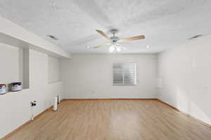 Empty room featuring ceiling fan, a textured ceiling, and light wood-type flooring