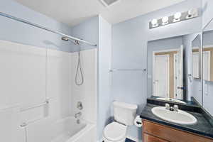 Full bathroom with vanity,  shower combination, a textured ceiling, and toilet