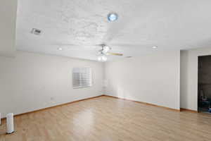 Unfurnished room featuring a textured ceiling, light hardwood / wood-style flooring, and ceiling fan